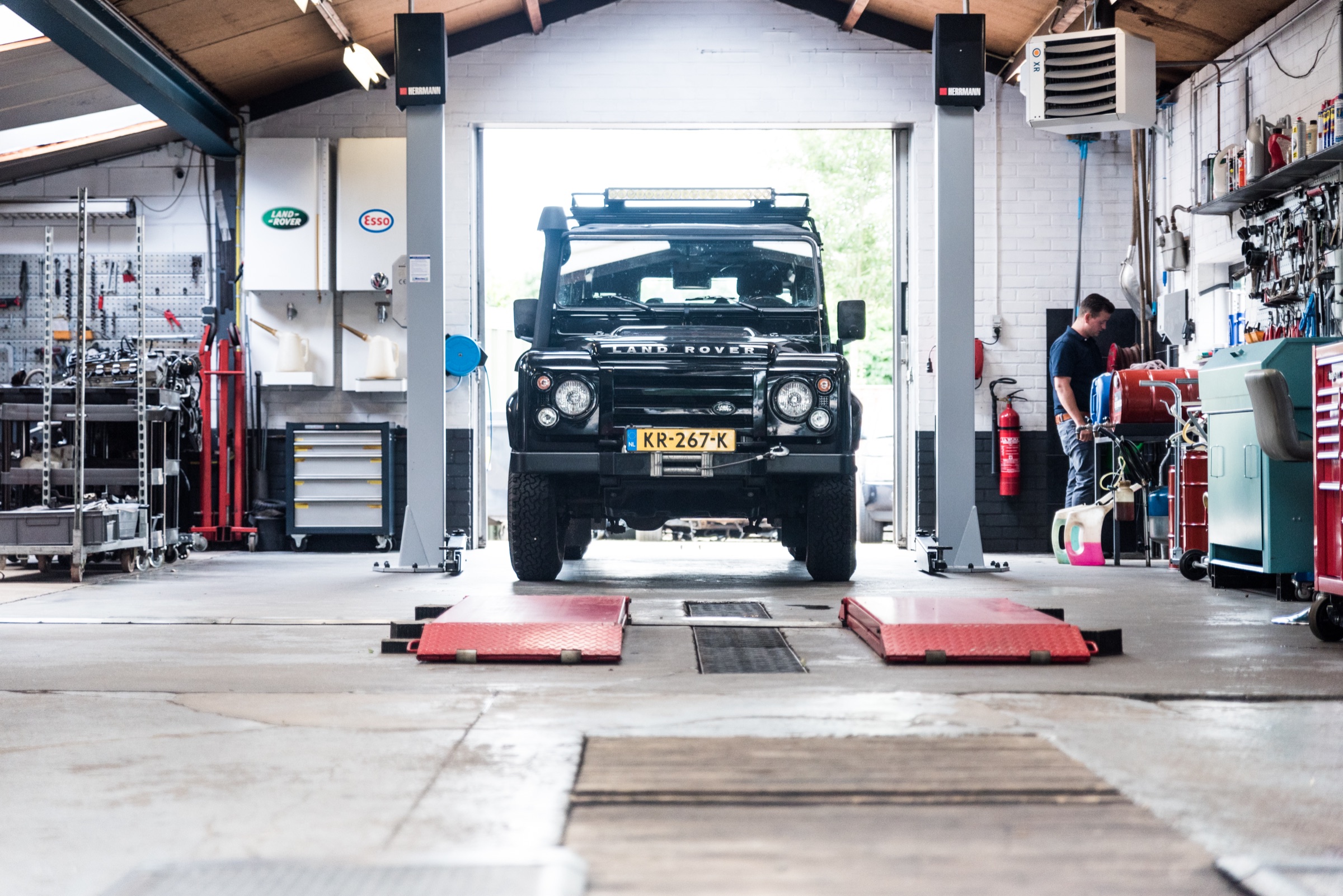 Zwarte Land Rover Defender in de werkplaats van Autobedrijf J. van Dreven, tussen twee brugliften