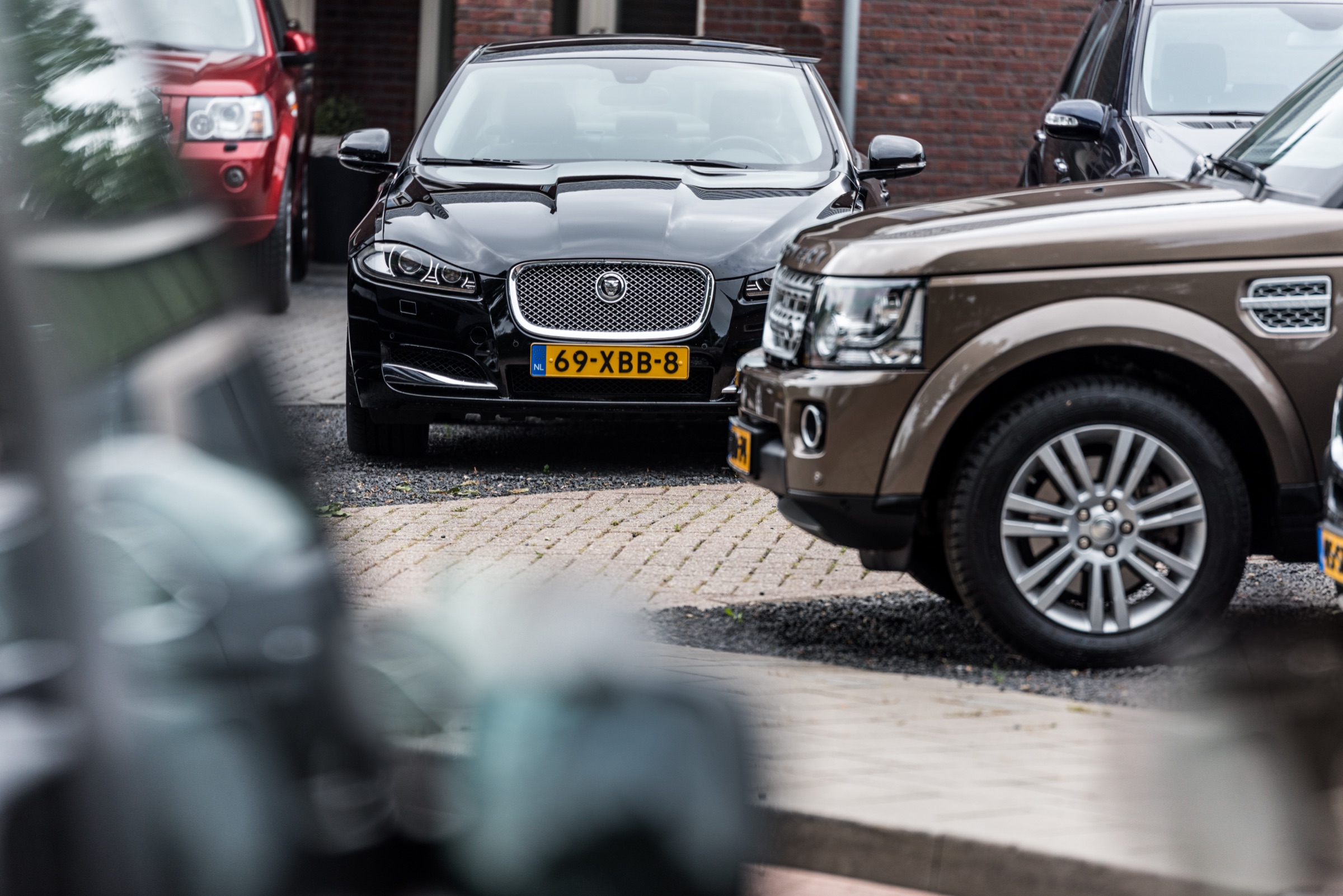 Een zwarte Jaguar XF en een bruine Land Rover Discovery 4 op het terrein