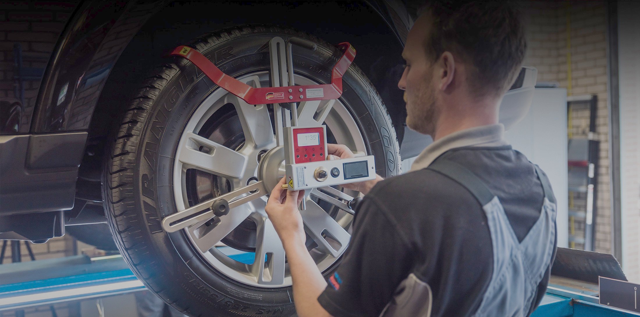 Monteur met uitlijnapparatuur op het wiel van een auto