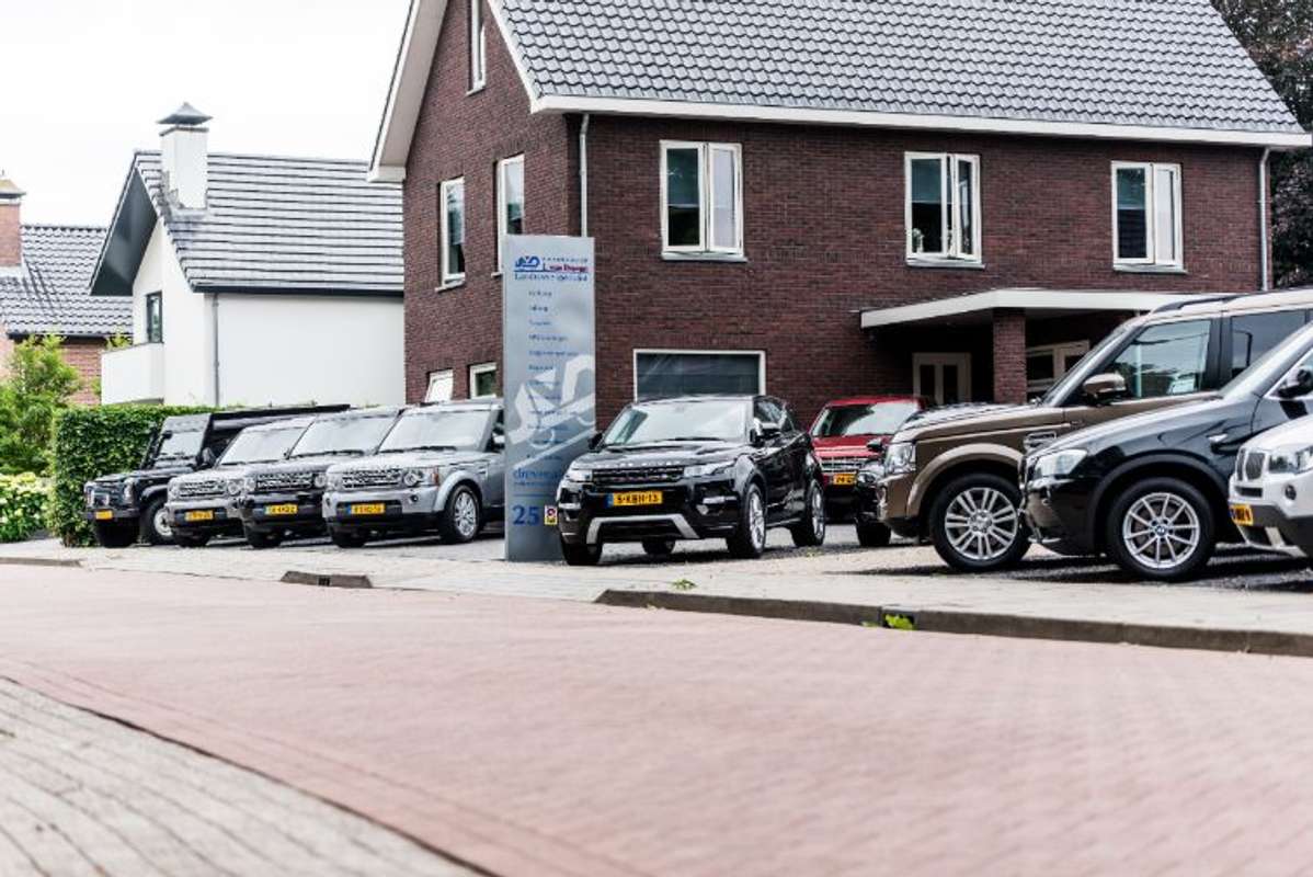 Het pand van Autobedrijf J. van Dreven met reclamezuil en een rij Land Rovers en Range Rovers